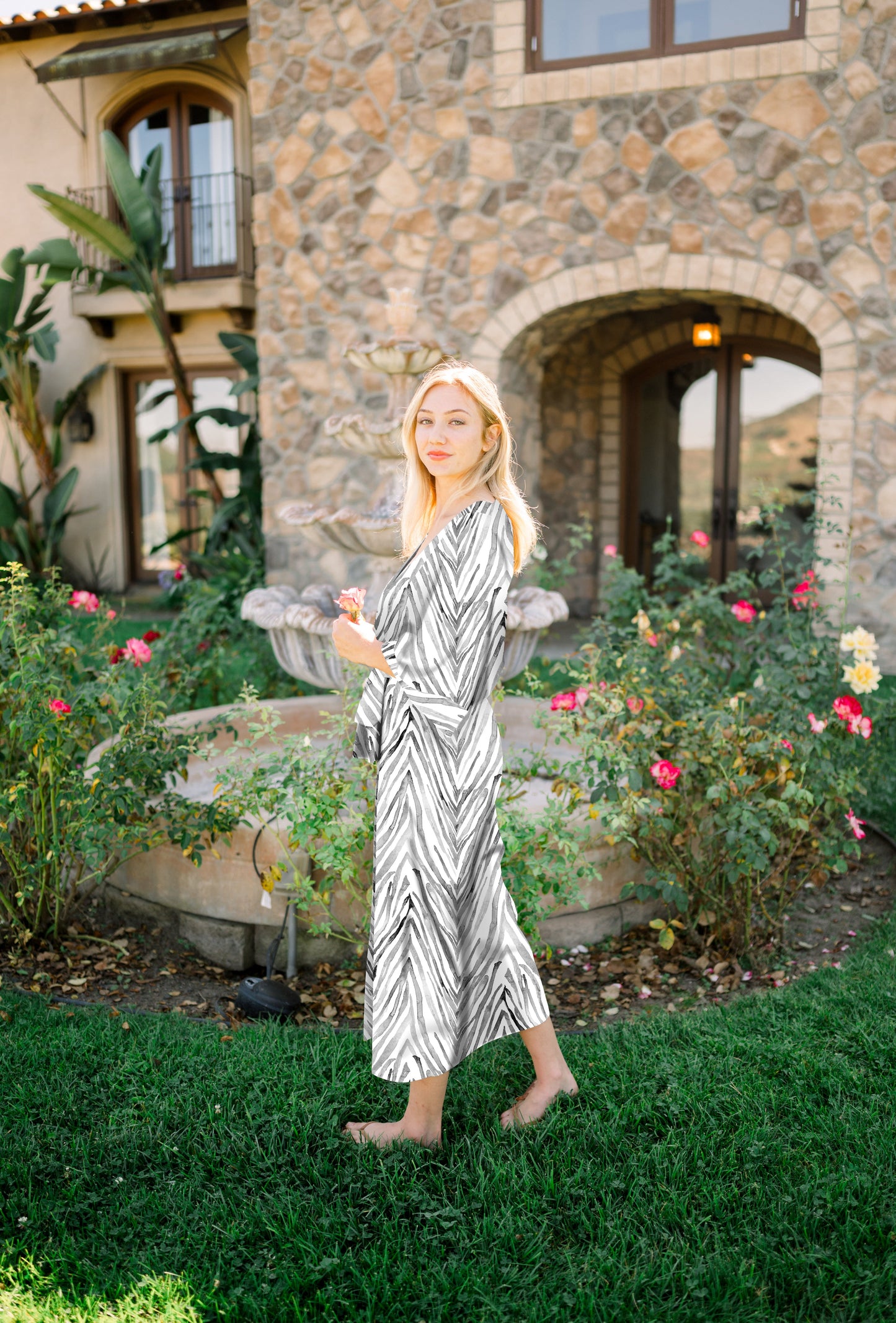 Woman wearing kimono robe in Zebra standing outside near a flower garden