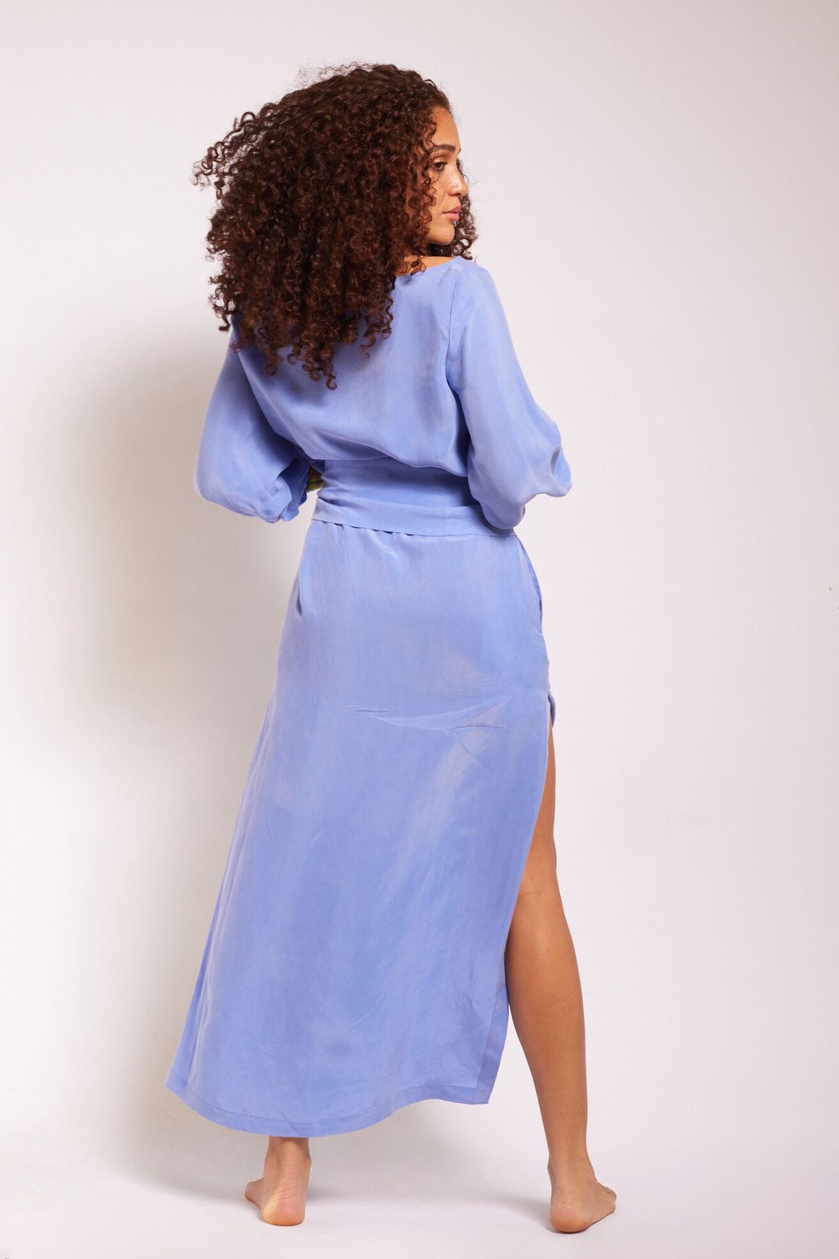 back view of woman wearing lavender kaftan duster with embroidered sleeves made from recycled materials