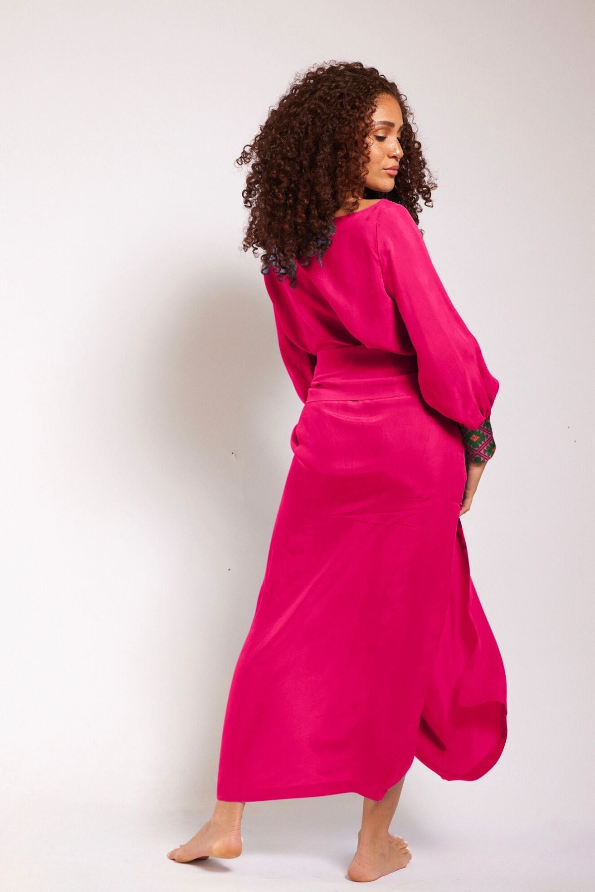 back view of woman wearing a magenta kaftan duster with embroidered sleeves made from recycled materials