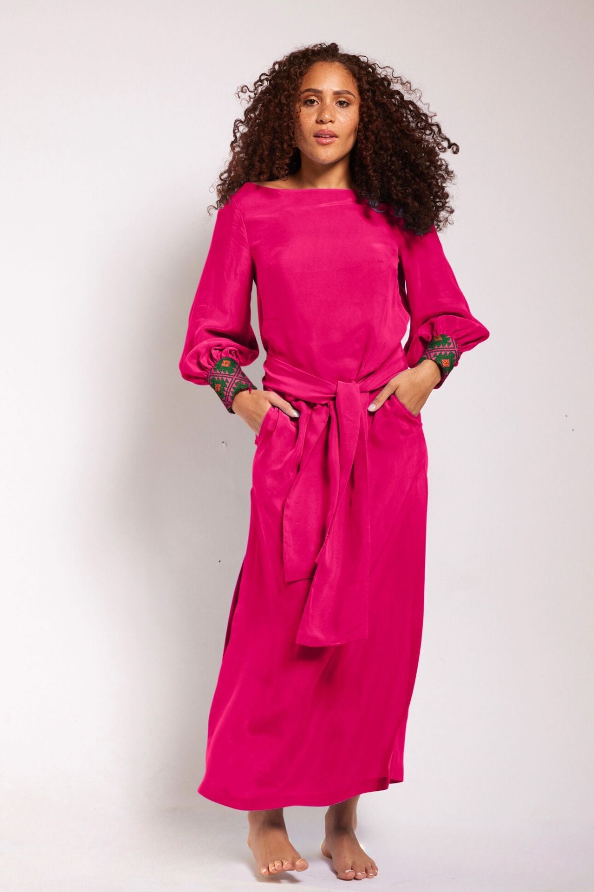 front profile view of woman wearing a magenta kaftan duster with embroidered sleeves made from recycled materials 4