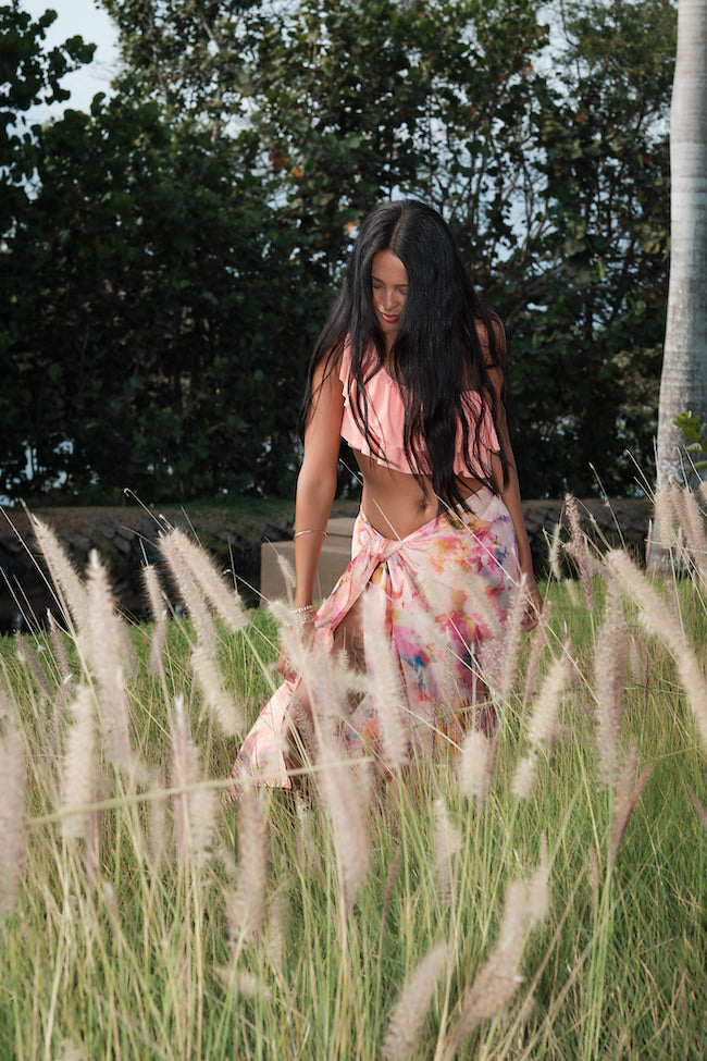 woman outside modelling all over peach floral sarong beachwear made from recycled textiles