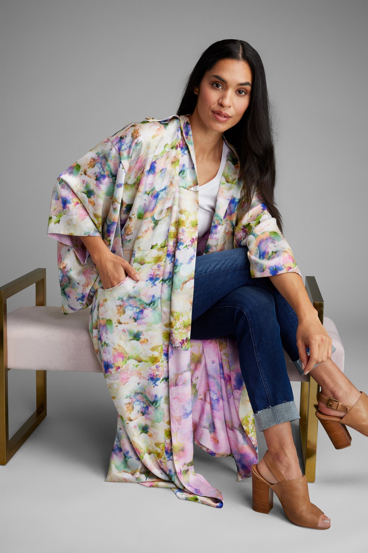 Woman lounging on a chair wearing an all over floral print kimono duster made from recycled materials 2