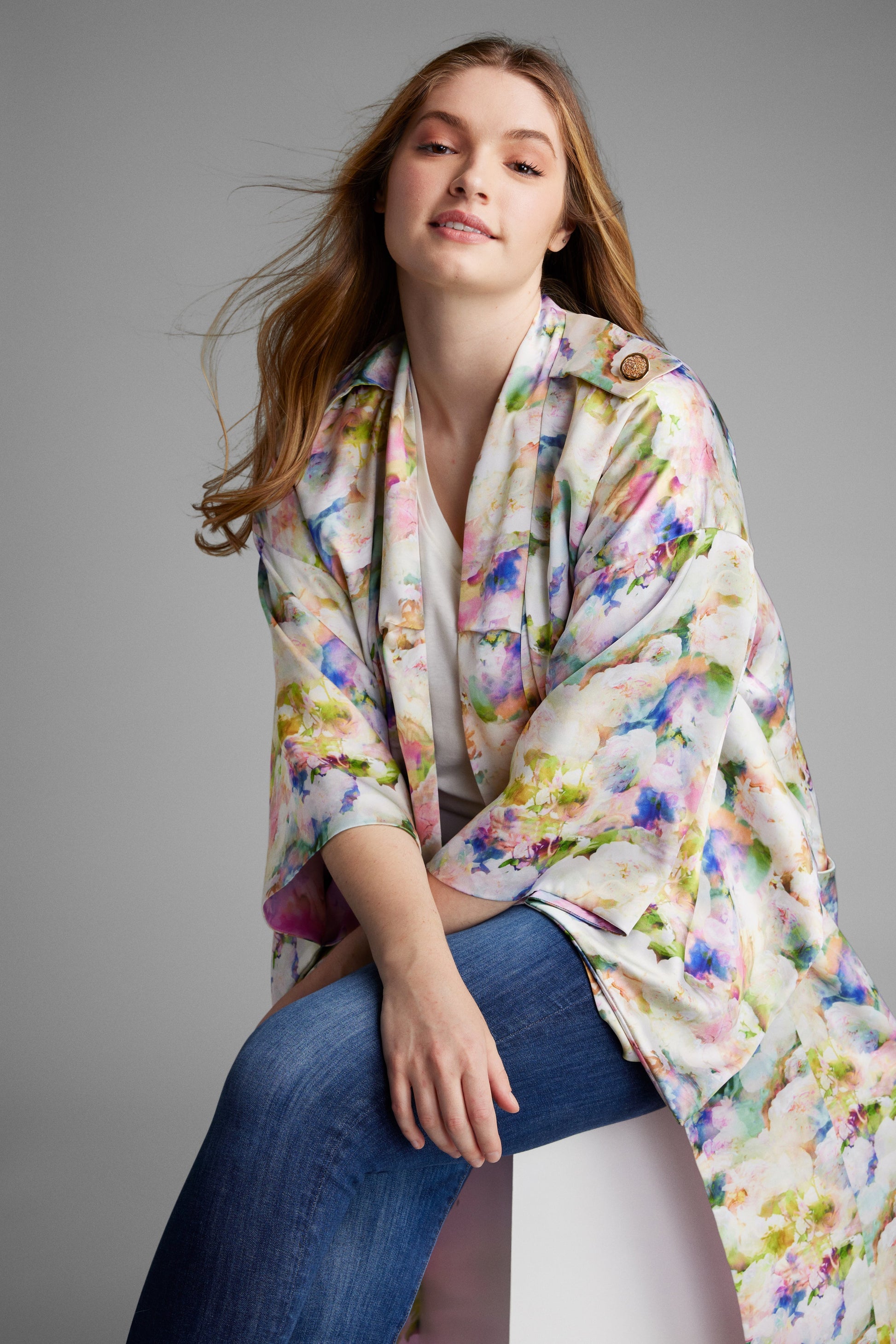 Woman lounging on a chair wearing an all over floral print kimono duster made from recycled materials 3
