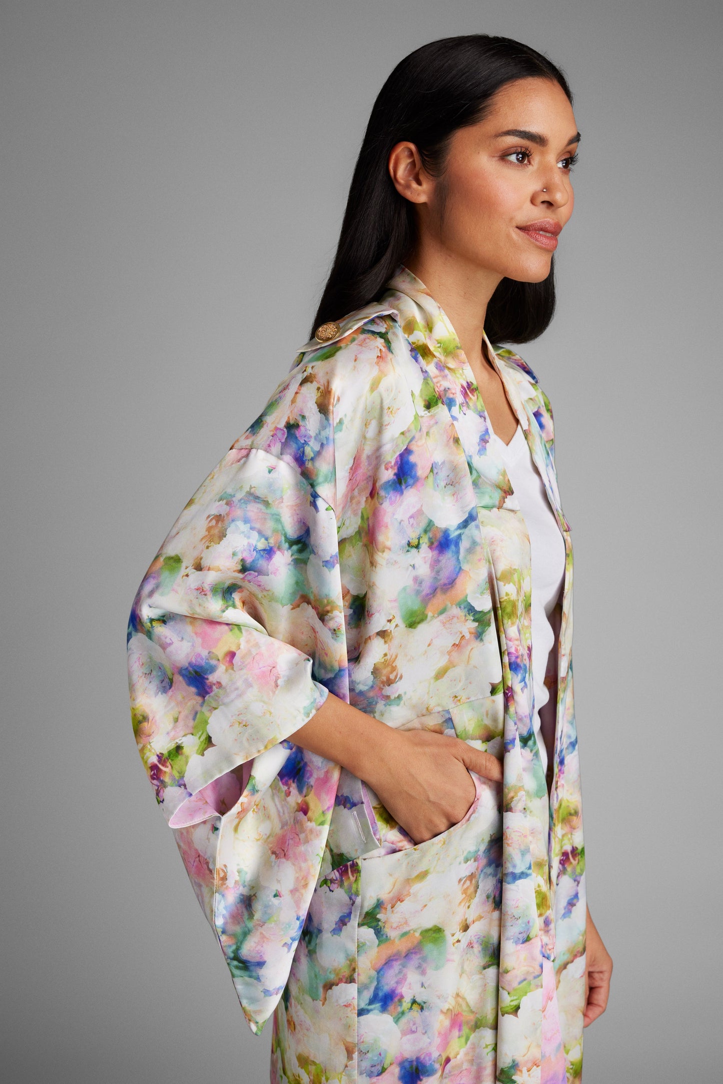 Side profile of woman with hand in her pocket wearing an all over floral printed kimono duster made from recycled materials