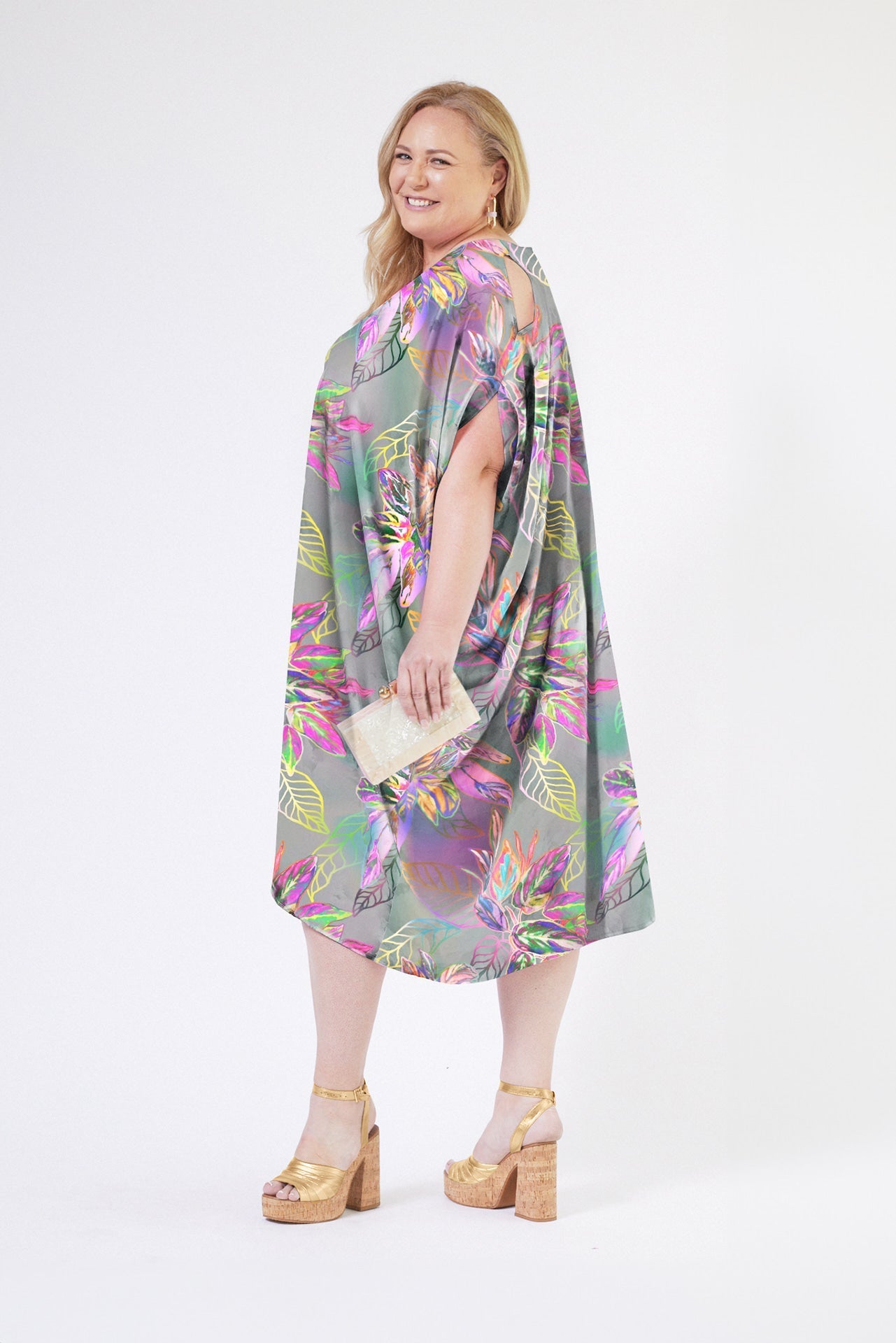 side view of woman wearing all over tropical print kaftan duster with front zipper made from recycled materials