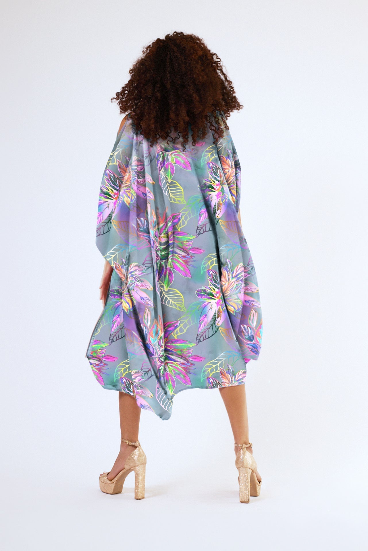 back view of woman wearing all over tropical print kaftan duster with front zipper made from recycled materials