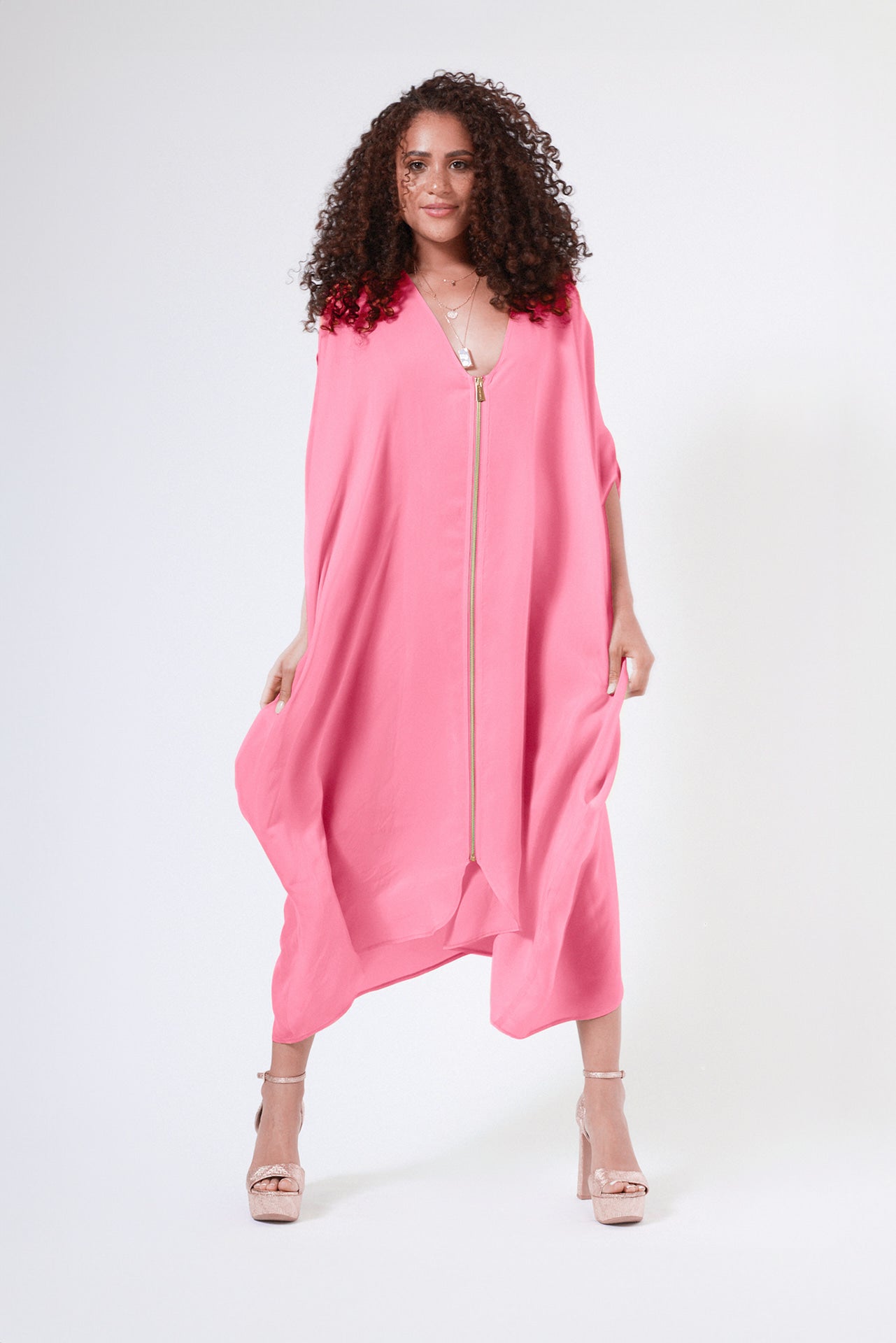 woman wearing bubble gum pink kaftan duster with front zipper made from recycled materials