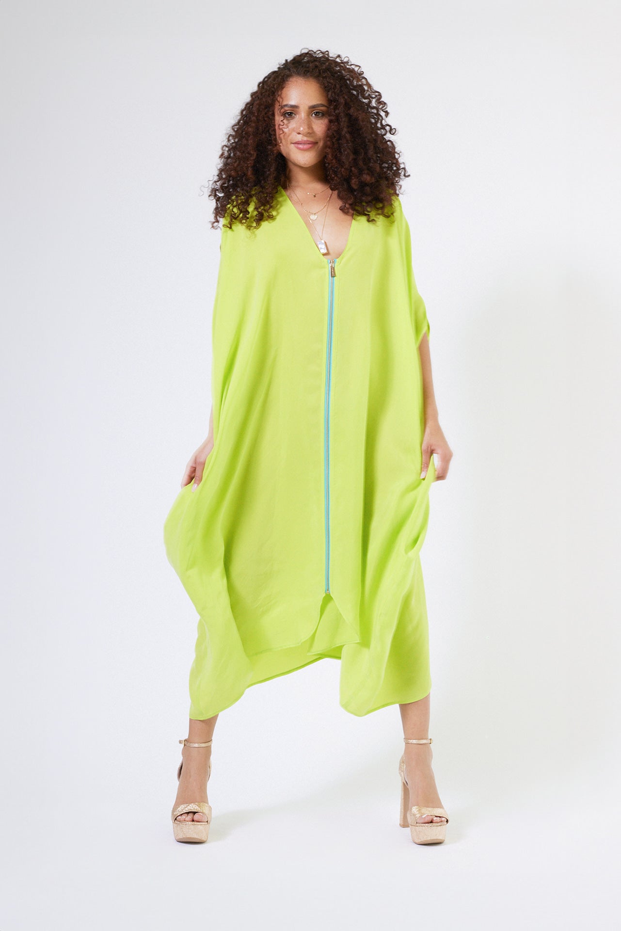 woman wearing bright yellow kaftan duster with front zipper made from recycled materials