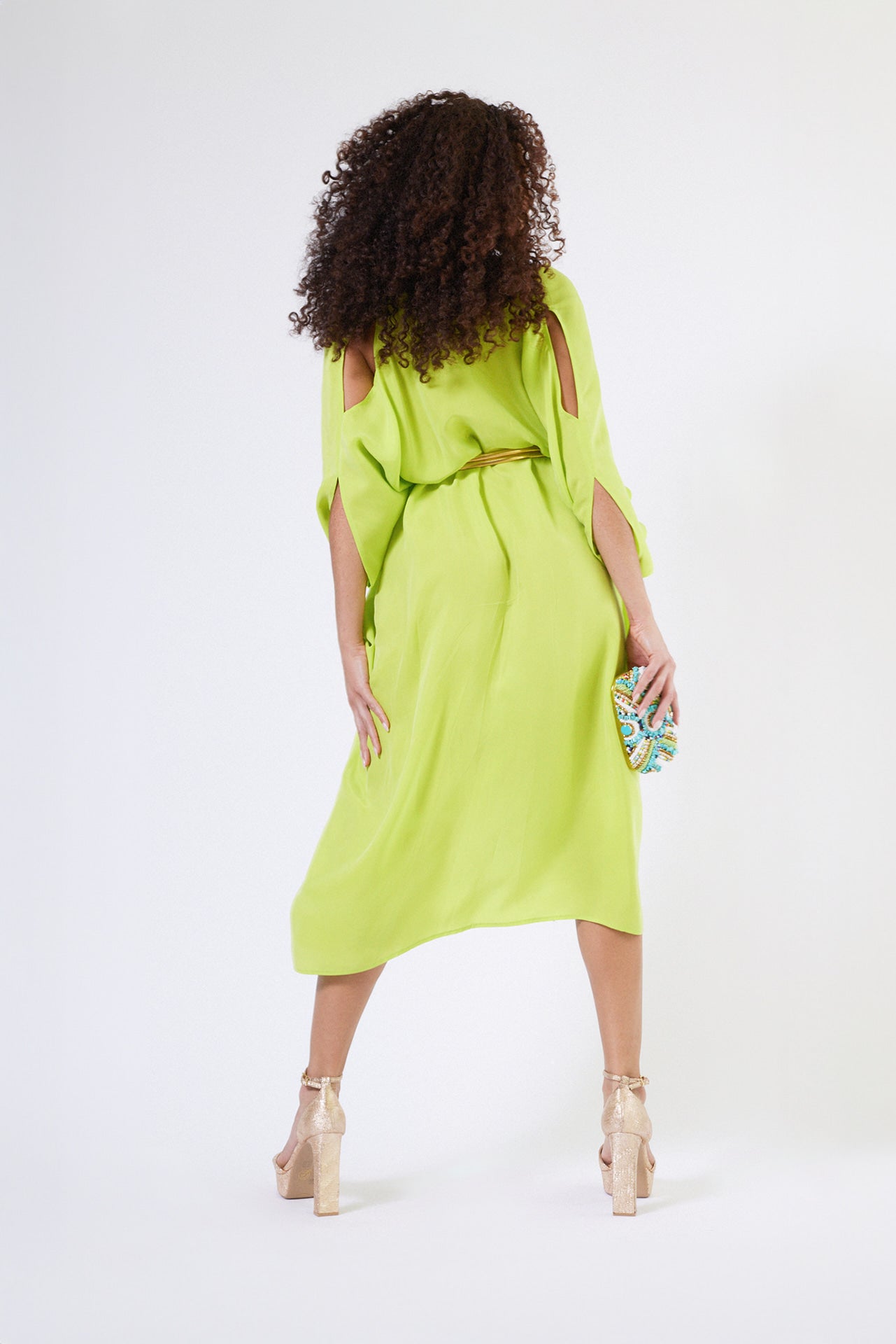 back view of woman wearing bright yellow kaftan duster with front zipper made from recycled materials 3