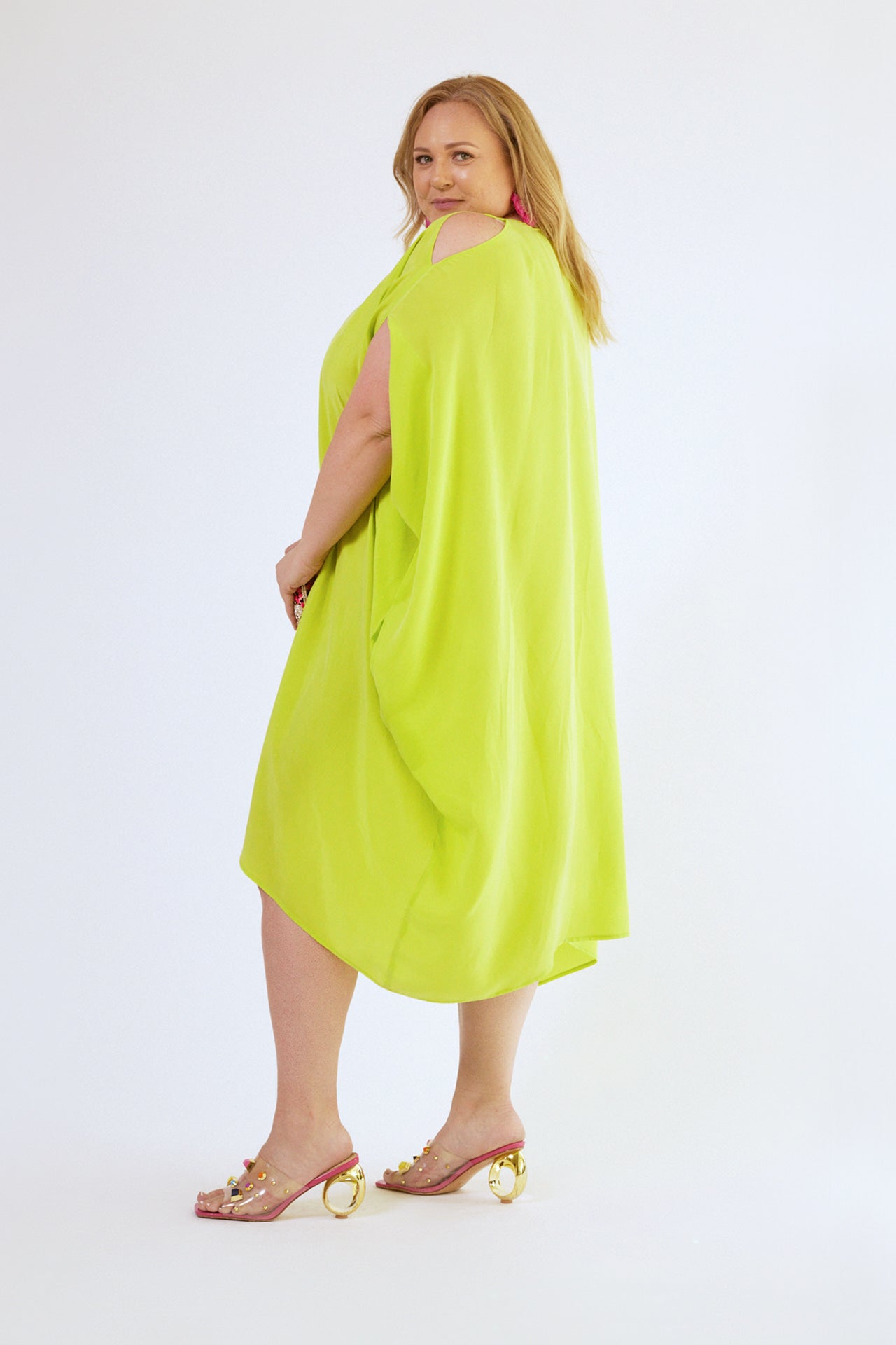back view of woman wearing bright yellow kaftan duster with front zipper made from recycled materials 4