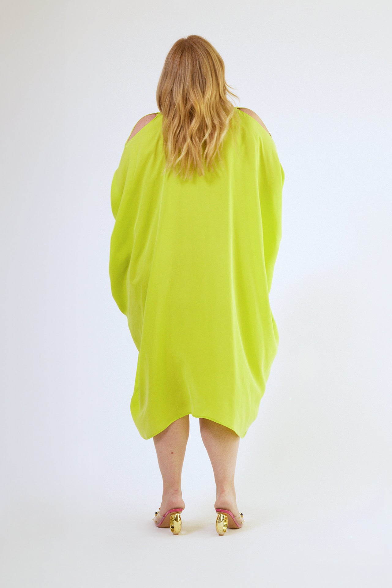 back view of woman wearing bright yellow kaftan duster with front zipper made from recycled materials 6