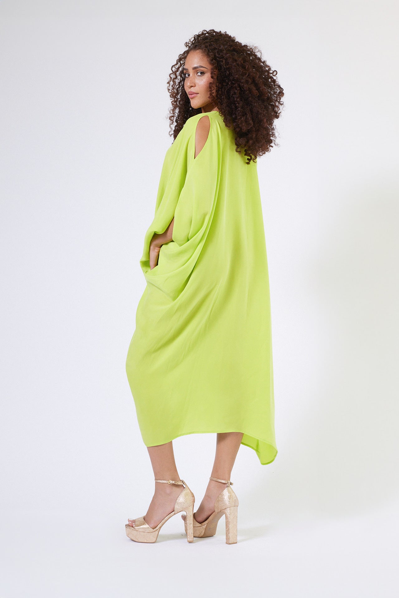 back view of woman wearing bright yellow kaftan duster with front zipper made from recycled materials