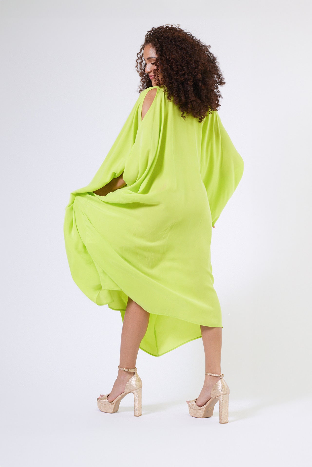 back view of woman wearing bright yellow kaftan duster with front zipper made from recycled materials 2