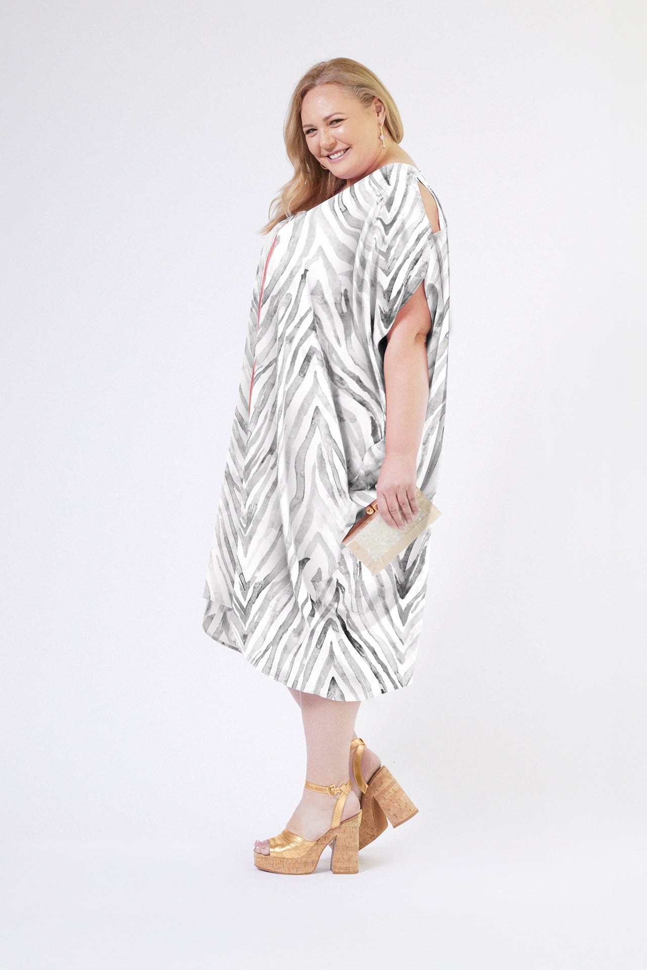 front view of woman wearing an all over grey and white zebra print kaftan duster with zipper made from recycled materials