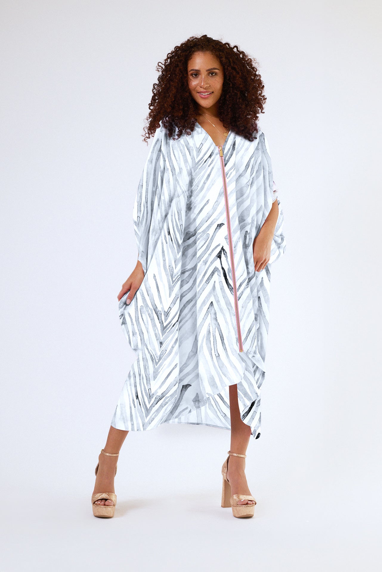 front profile of woman wearing an all over grey and white zebra print kaftan duster with zipper made from recycled materials