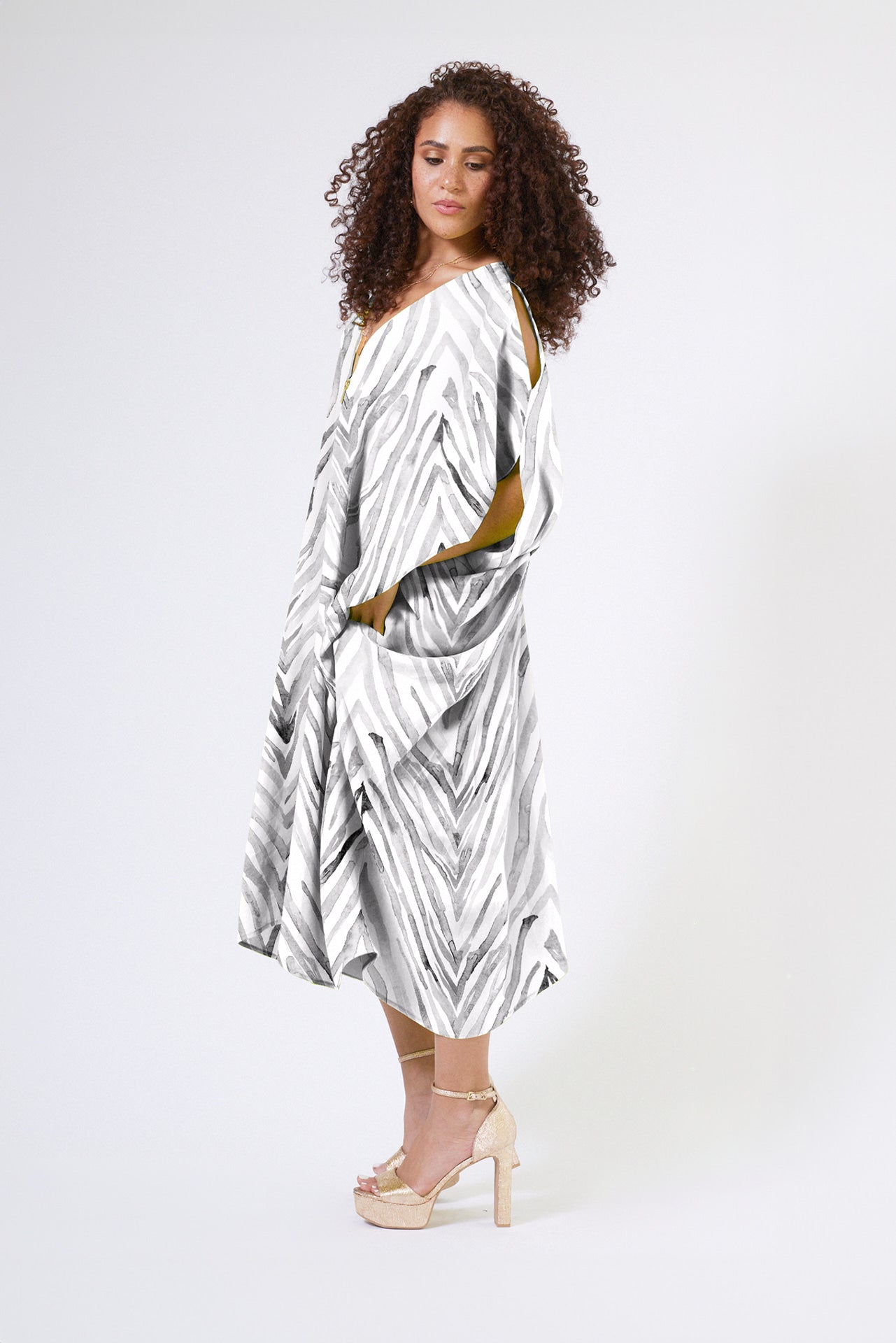 front profile of woman wearing an all over grey and white zebra print kaftan duster with zipper made from recycled materials 2