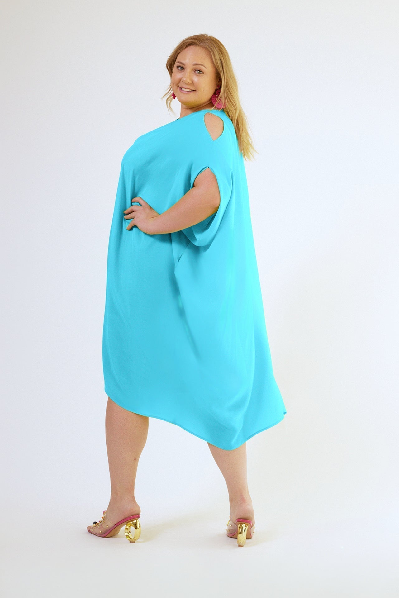 side view of woman wearing bright turquoise kaftan duster with front zipper made from recycled materials 2