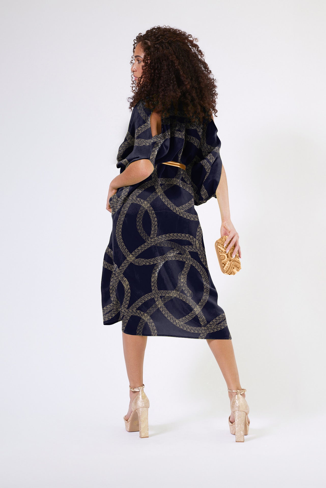back view of woman modelling gold and black chain printed kaftan duster with front zipper made from recycled materials