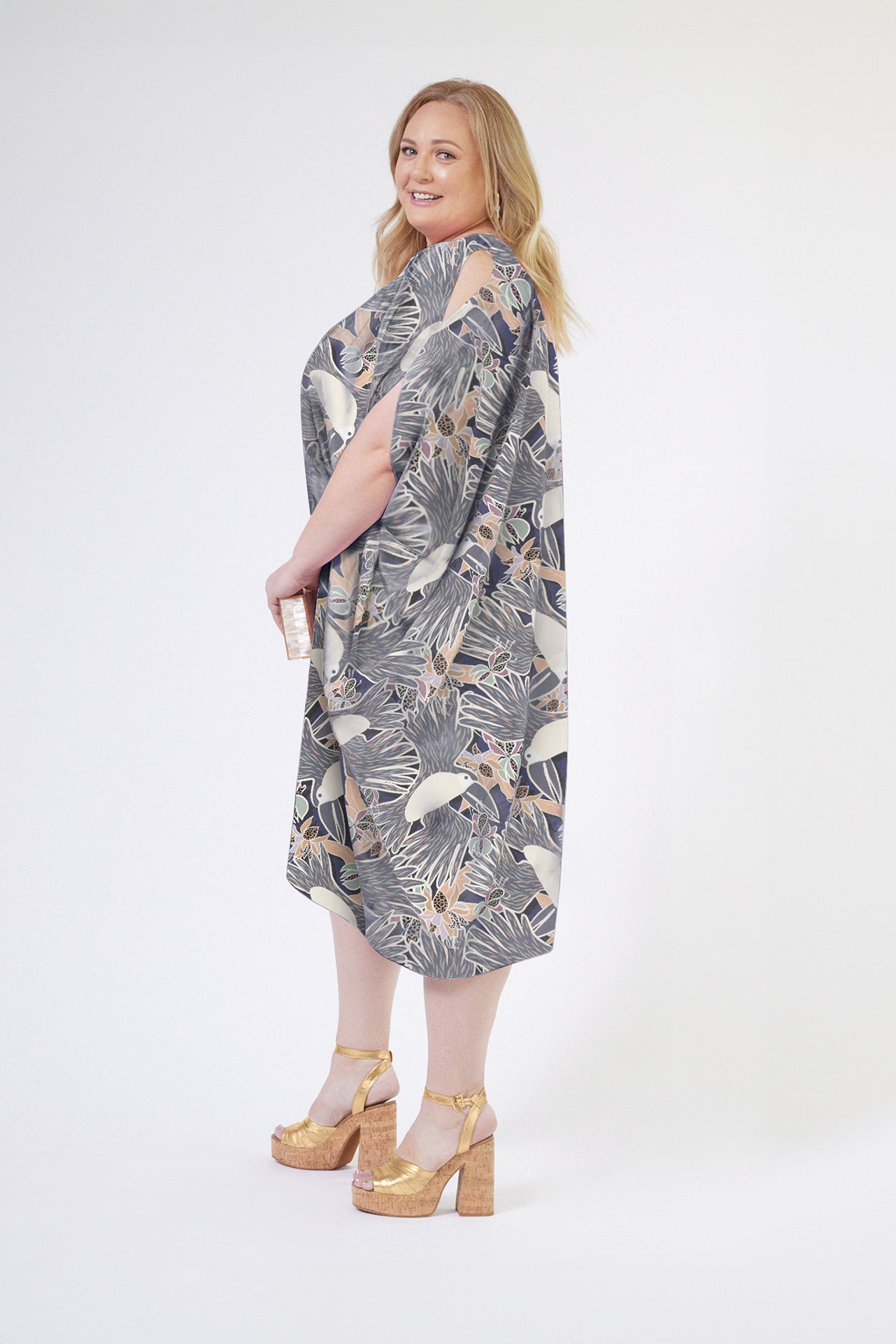 side view of woman wearing grey yellow and white all over tropical print kaftan duster with zipper made from recycled materials 3