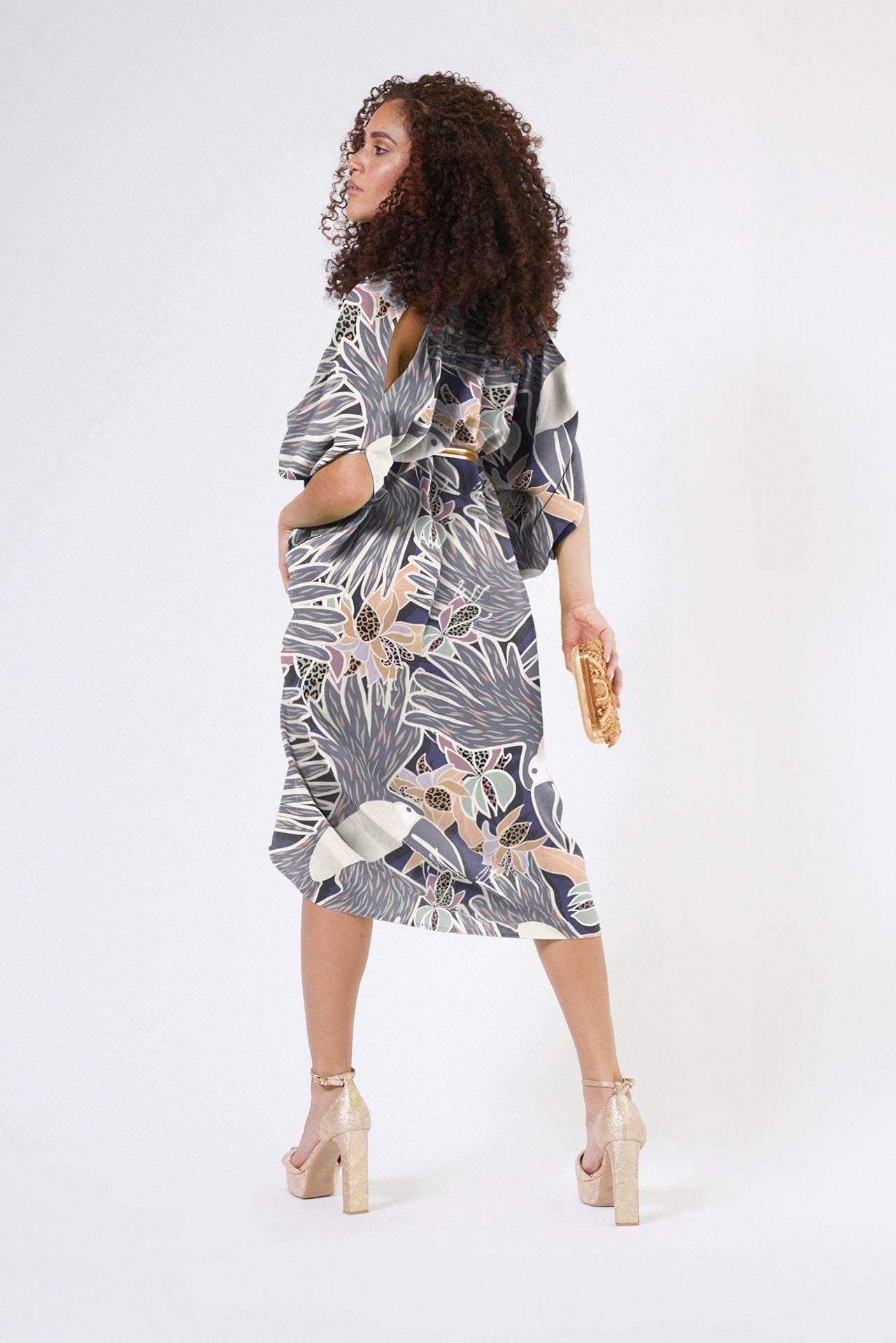 back profile of woman wearing navy and white toucan printed kaftan duster with front zipper made of recycled materials