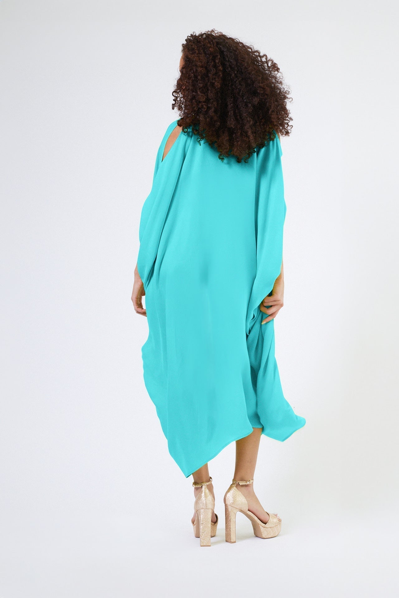 back view of woman wearing bright turquoise kaftan duster with front zipper made from recycled materials
