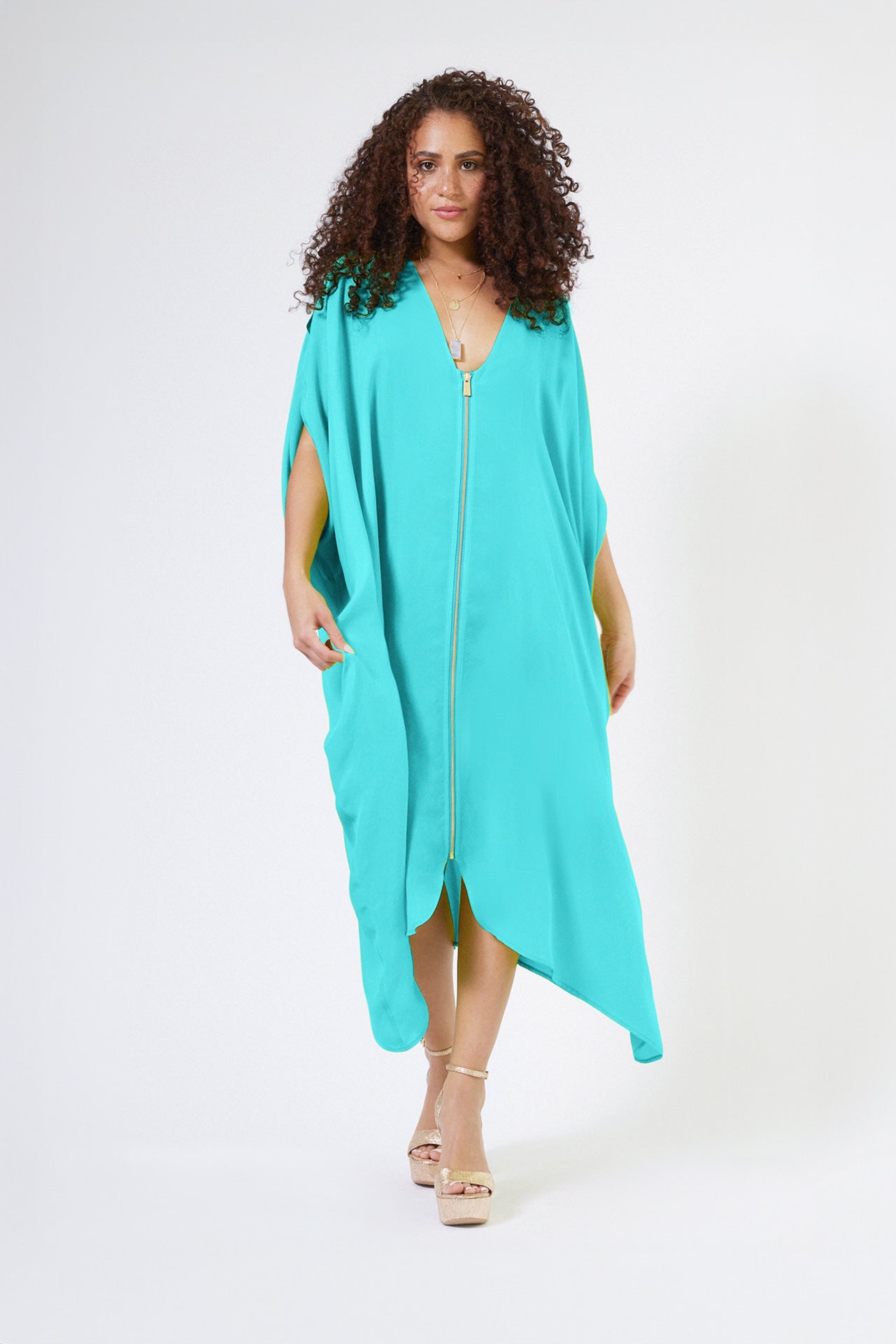 front view of woman wearing bright turquoise kaftan duster with front zipper made from recycled materials 2