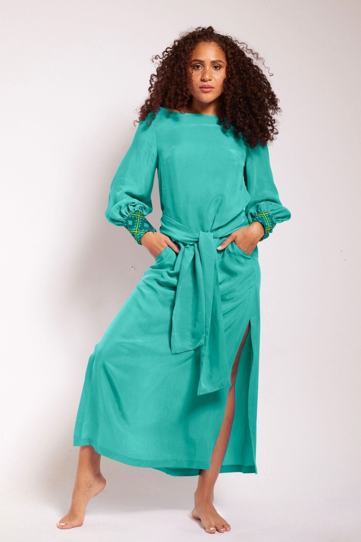 front view of woman wearing turquoise kaftan duster with embroidered sleeves made from recycled materials