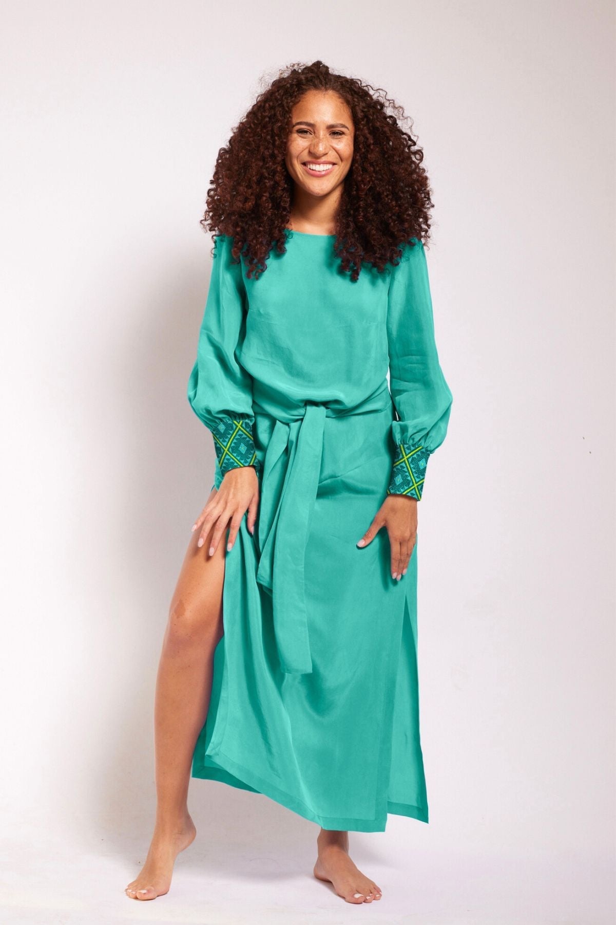 front view of woman wearing turquoise kaftan duster with embroidered sleeves made from recycled materials 2