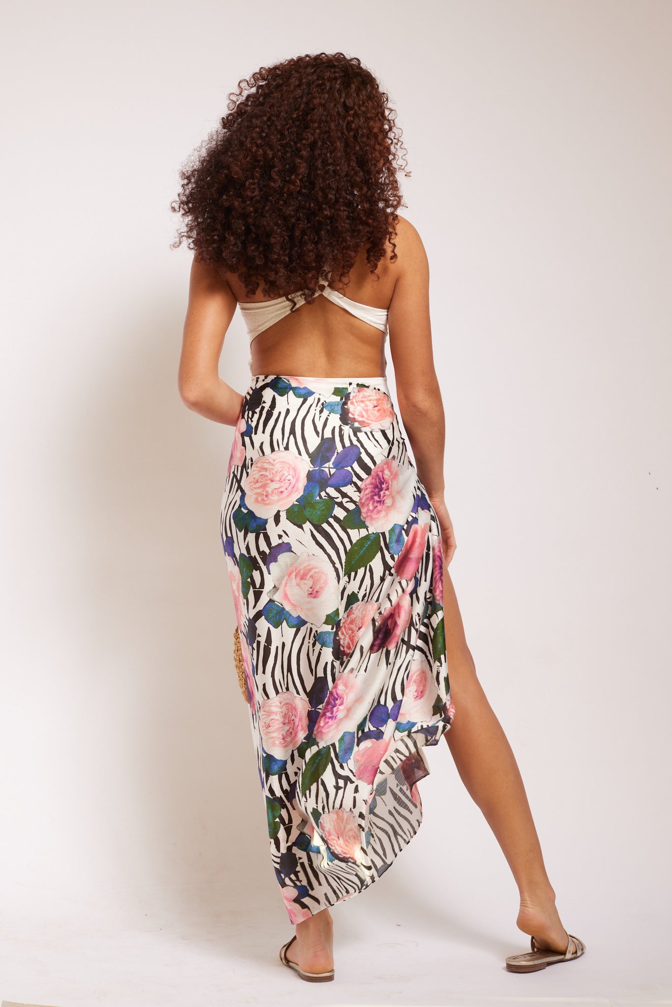 back view of woman modelling all over peach poppy print sarong beachwear with crinkled chiffon and tassel ends